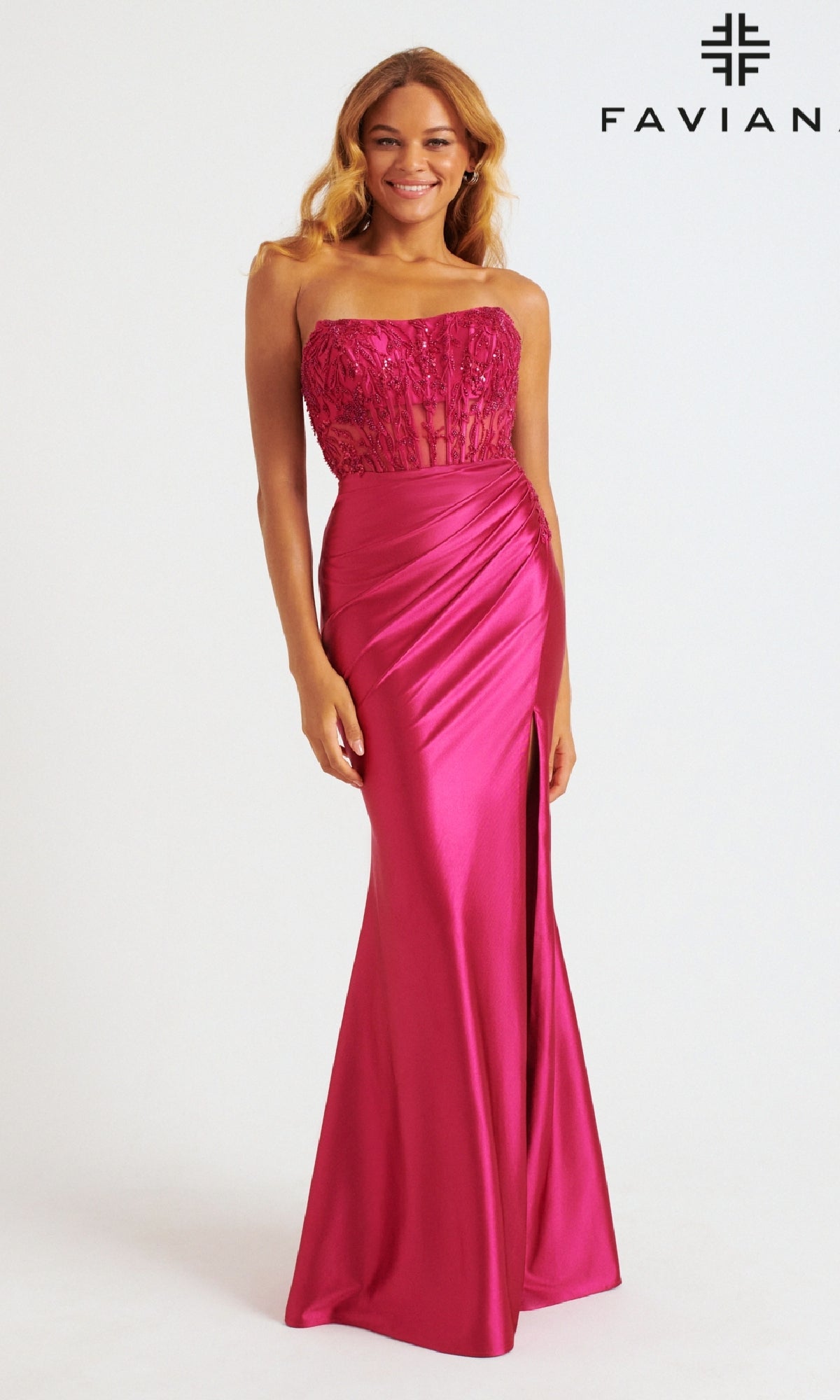 A woman in the Faviana 11246 long prom dress, featuring a strapless satin corset bodice, floor-length magenta skirt, and side draping, stands before a plain background with the FAVIAN logo in the top right corner.